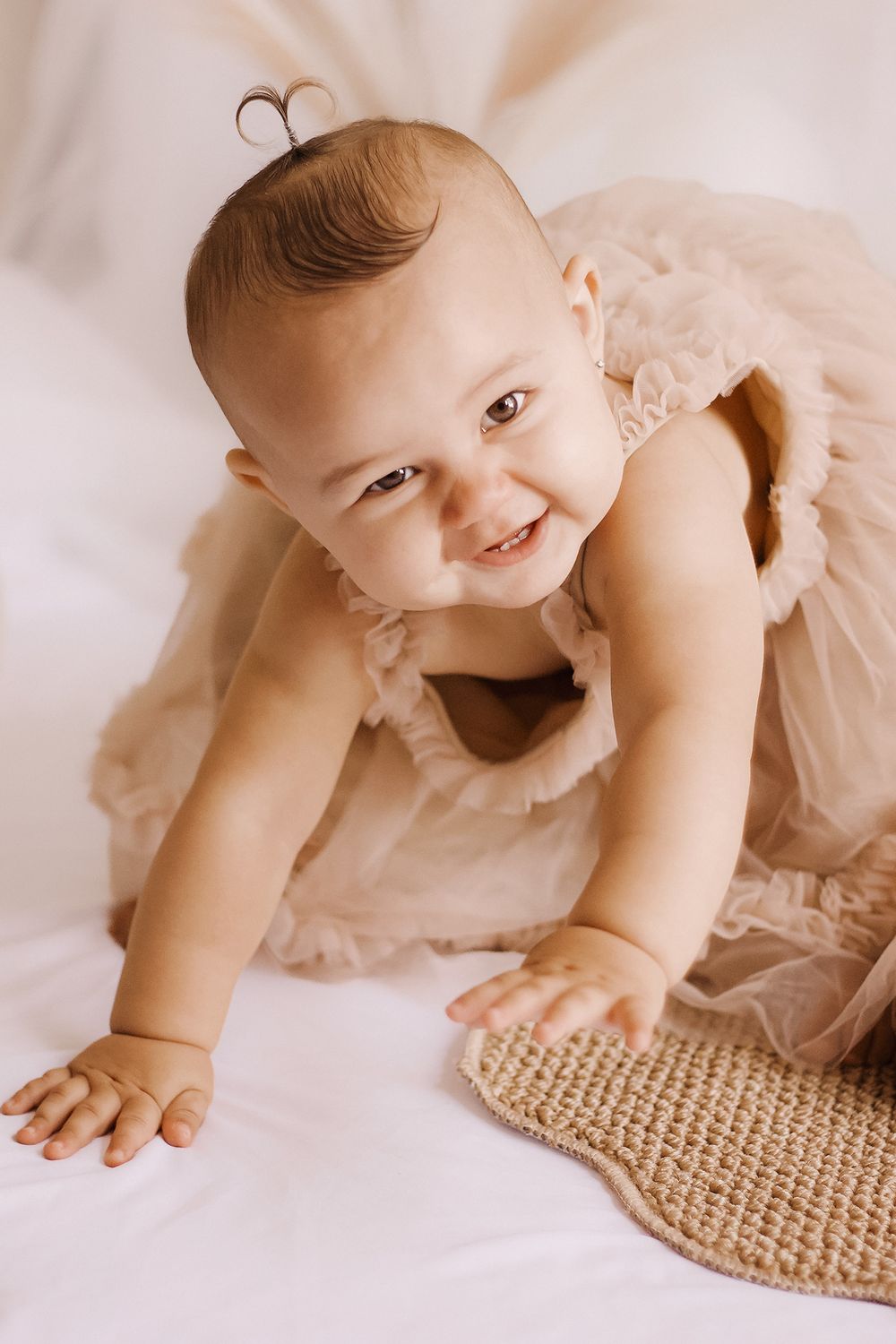 Baby in a tulle dress crawling towards the camera, smiling