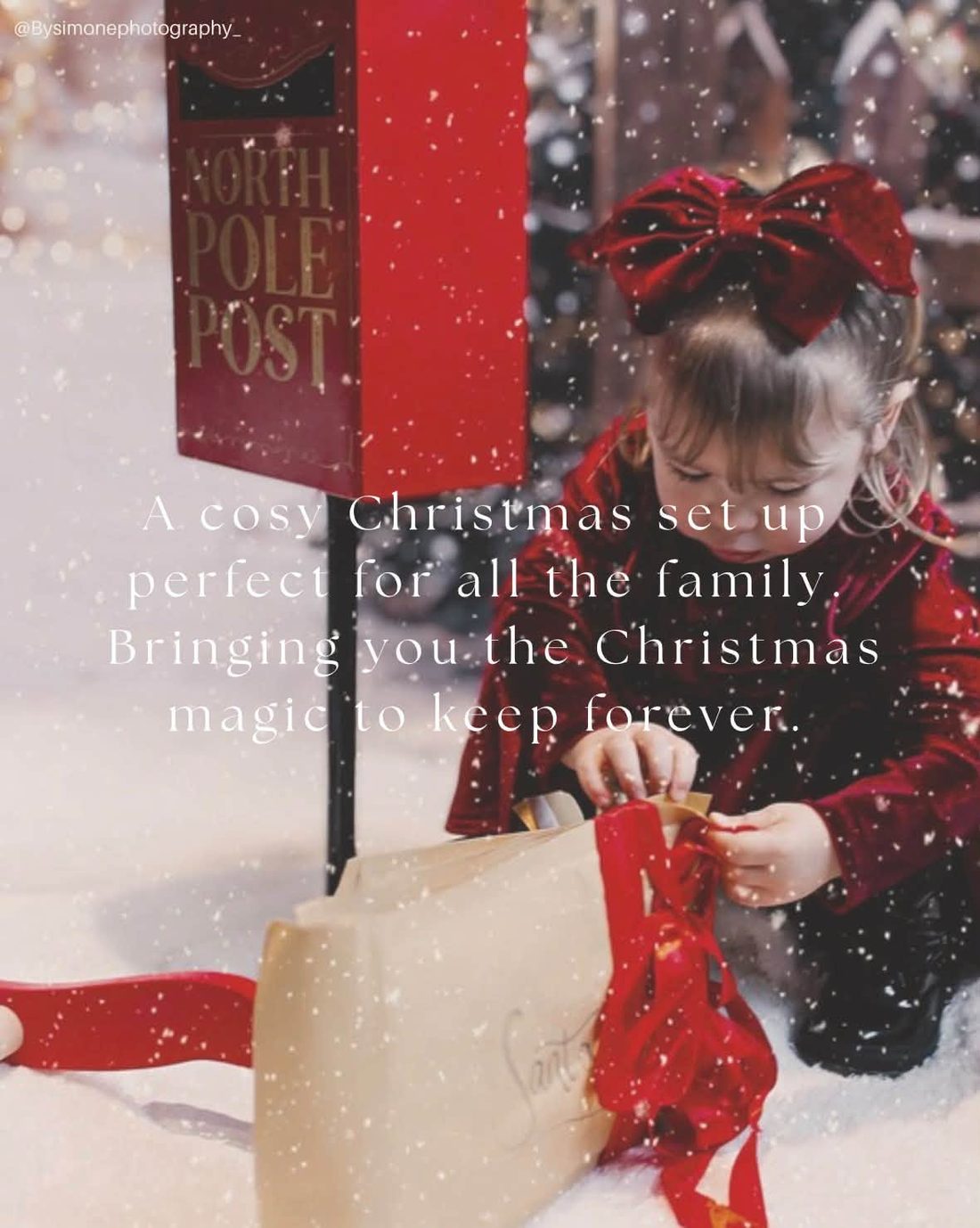 Little girl in red velvet opening a parcel by a North Pole Post box in falling snow